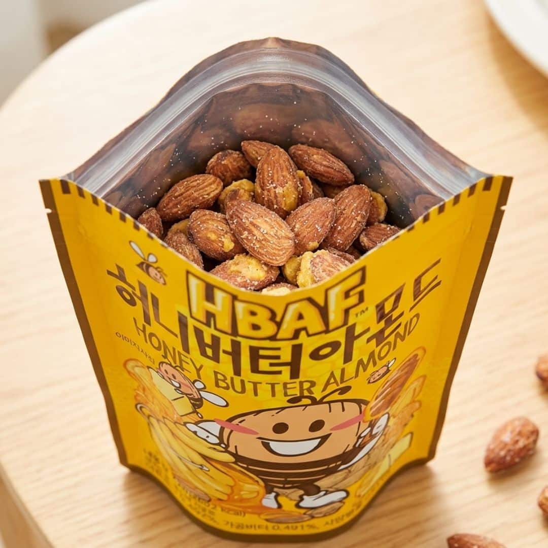 hbaf honey butter almond 1 | Snack Affair Archives Yellow Honey Butter Almonds bag with almonds visible at the top, featuring a cheerful bee cartoon on the front.