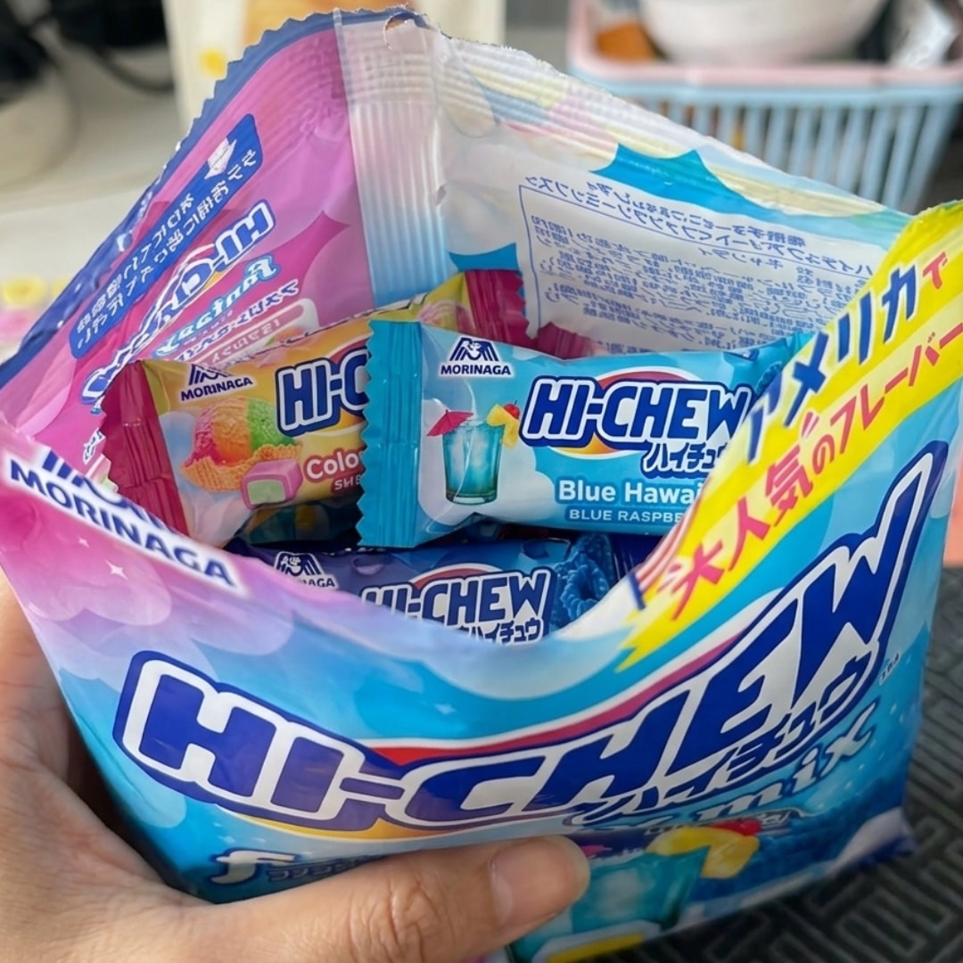 HiChew Fantasy Mix 1 | Snack Affair Archives Open bag of Morinaga Hi-Chew candies with blue Hawaii flavor, held in a hand, showing blue and colorful wrappers inside the bag.