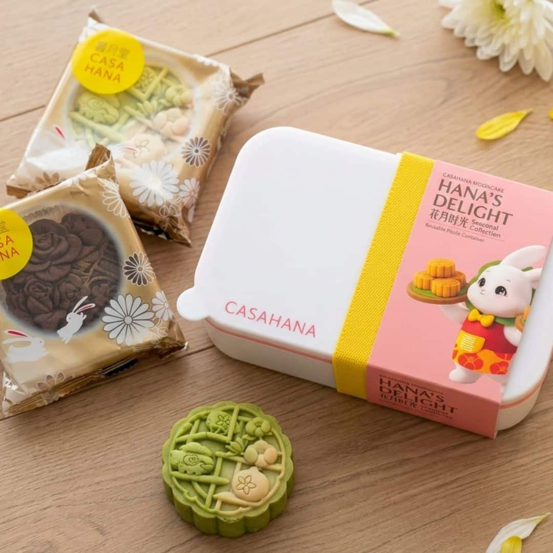 Casahana Hanas Delight Pistachio Mooncake Gift Set 2 | Snack Affair Archives Mooncake gift set by Casahana Hana's Delight: green tea mooncake, wrapped pastries, and a white box with yellow strap on a wooden surface.