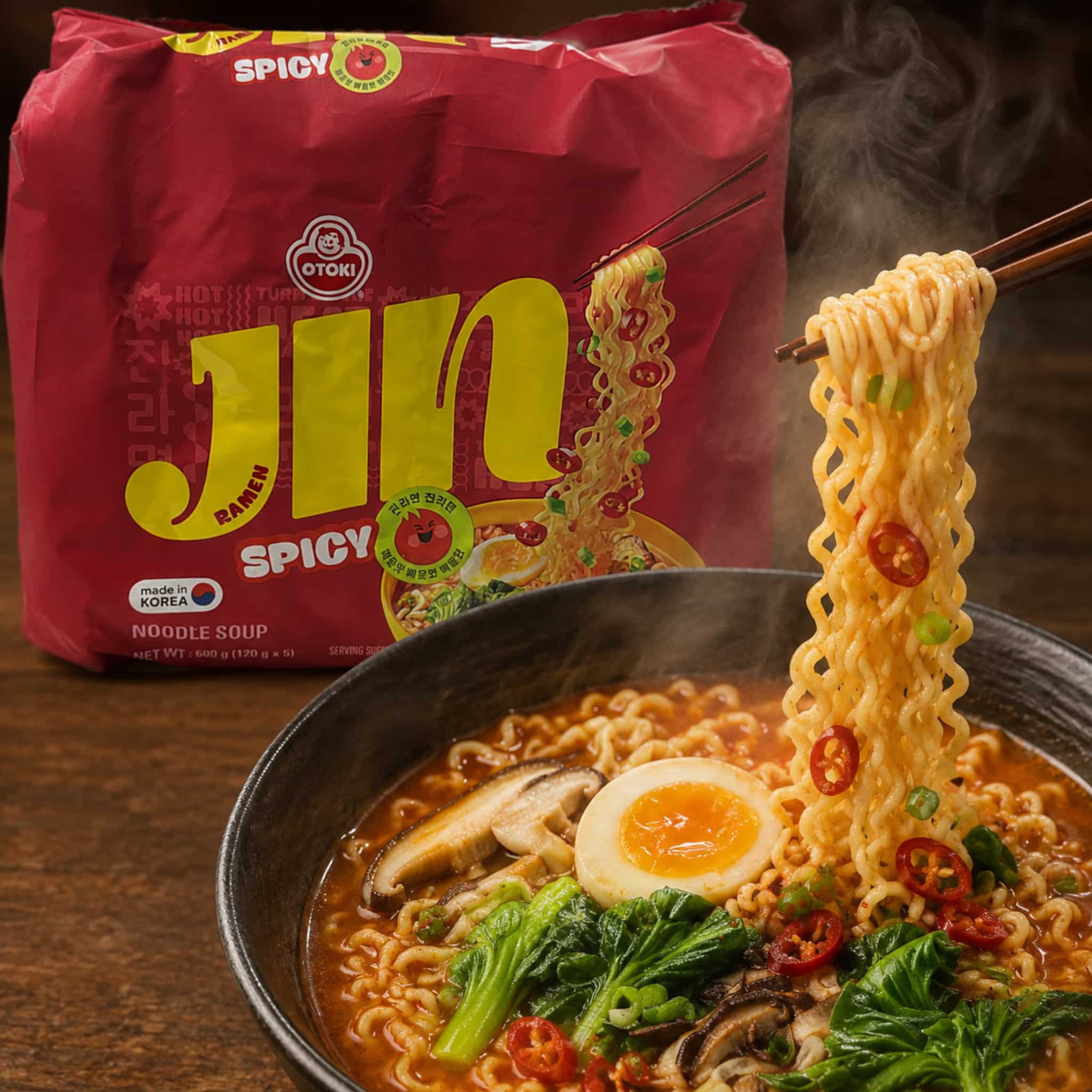 Otoki Jin Ramen Spicy 5 Pack 600g Close Up | Snack Affair Archives Red spicy ramen packet beside a steaming bowl of noodles topped with greens, chili slices, and a halved boiled egg.