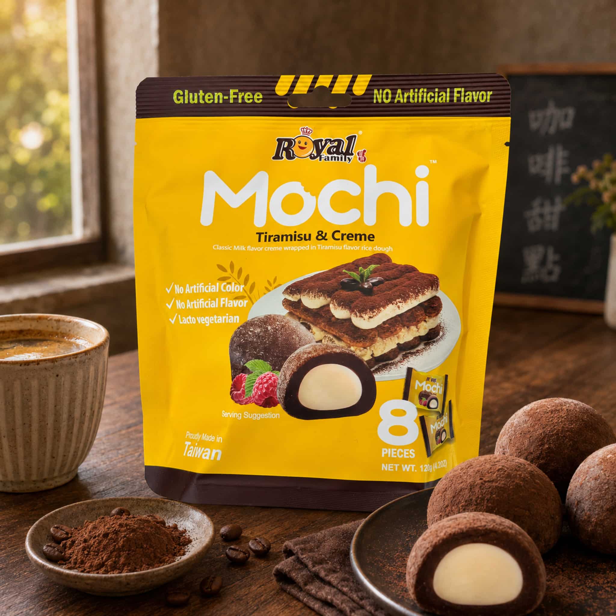 Royal Family Tiramisu Creme Mochi Lifestyle | Snack Affair Archives Bright yellow Mochi snack bag on a wooden table, surrounded by chocolate cookies and scattered coffee beans.