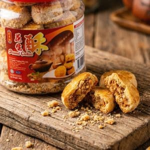 Jar of peanut cookies beside broken cookies on a rustic wooden board