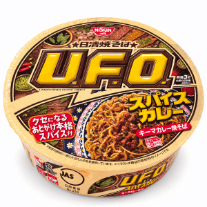 Close-up of a Nissin instant noodles cup lid with bold yellow letters and Japanese text, showing spices and noodles image.