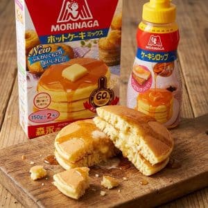 Archives Stack of fluffy pancakes with syrup on a wooden board, Morinaga pancake mix box and syrup bottle in the background.