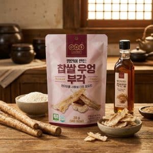 Archives Pink package of burdock root crisps on a wooden table, surrounded by bowls of chips, sesame sticks, and a bottle of oil in a rustic kitchen setting.